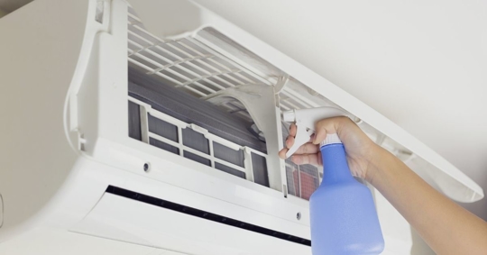 close up of a spray bottle near a AC unit air filters