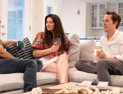 3 people sitting around a coffee table on a couch drinking
