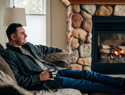 man sitting on couch in front of fireplace