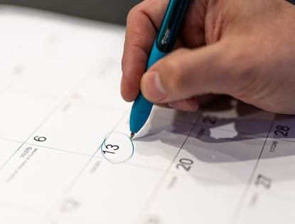 person's hand circling date on calendar