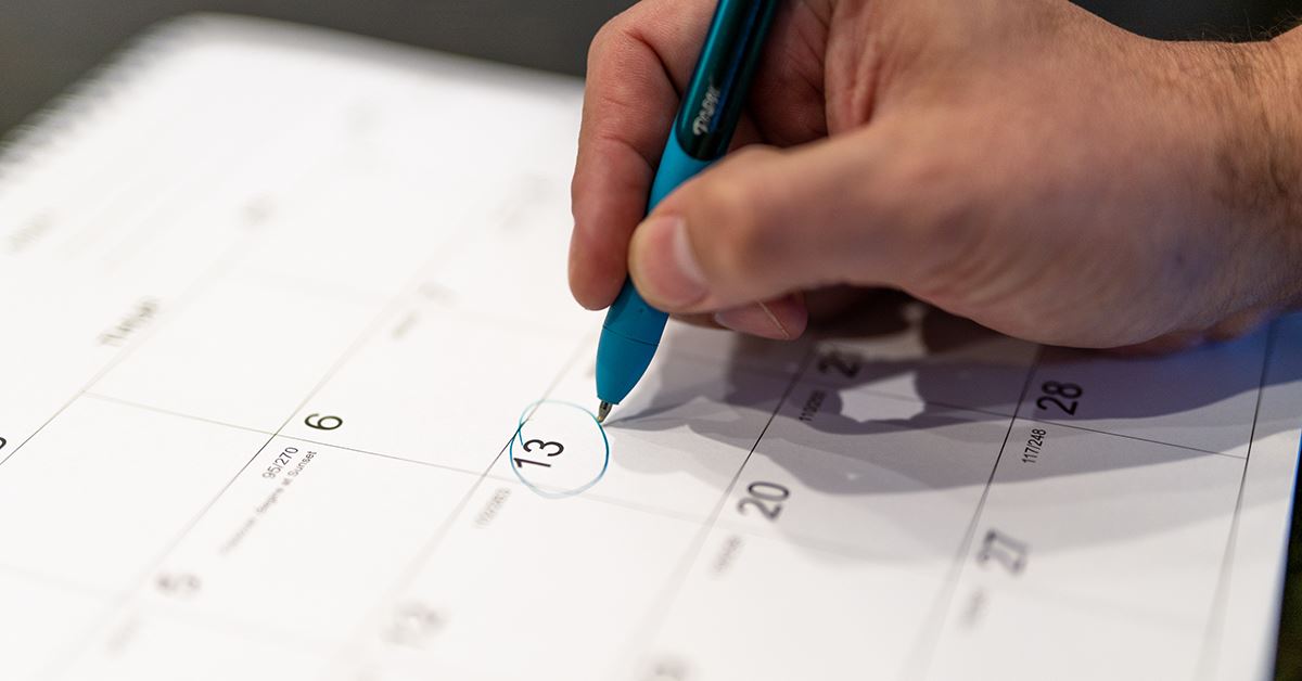 person's hand circling date on calendar